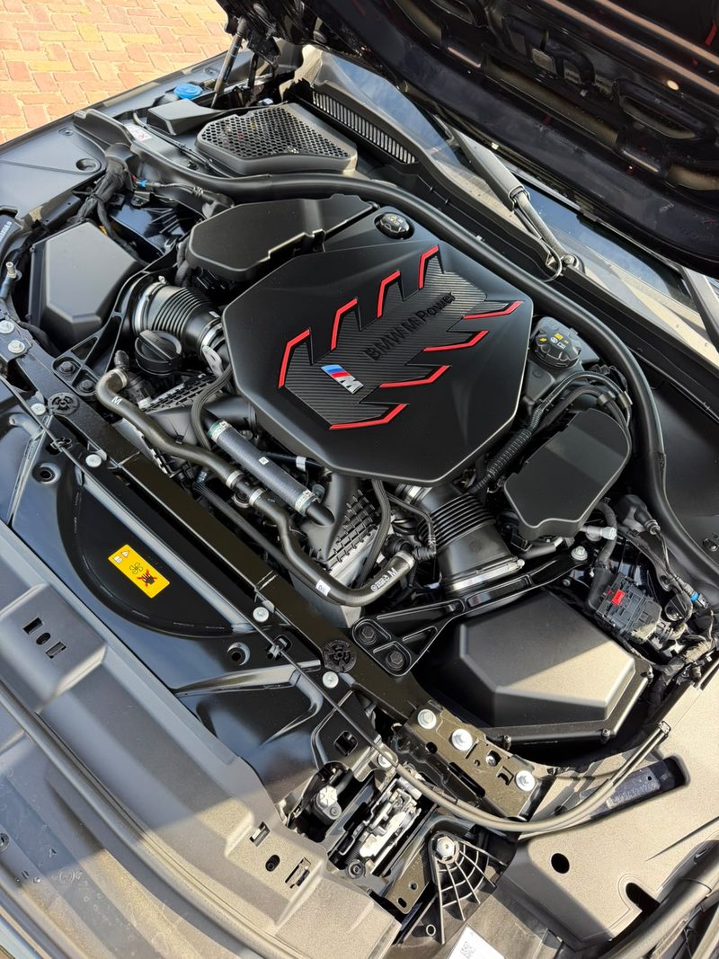 Gereinigde motorruimte van een BMW M met rode M Power-afdekking bij JS Detail Studio in IJmuiden