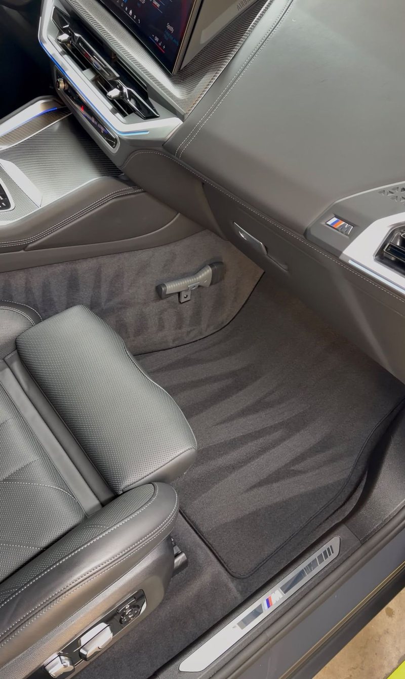 Gereinigd tapijt en vloermatten achterin een BMW XM na interieur detailing bij JS Detail Studio in IJmuiden