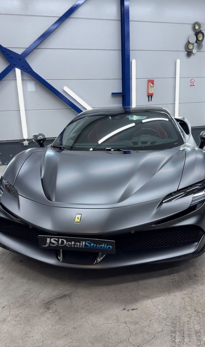 Matgrijze Ferrari SF90 Spider met gouden velgen vooraanzicht in de detailingstudio van JS Detail Studio in IJmuiden