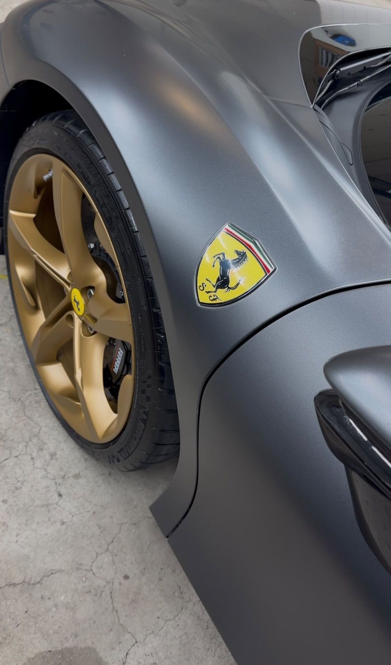 Gouden velg en Ferrari-schild op het spatbord van een matgrijze Ferrari SF90 Spider bij JS Detail Studio in IJmuiden